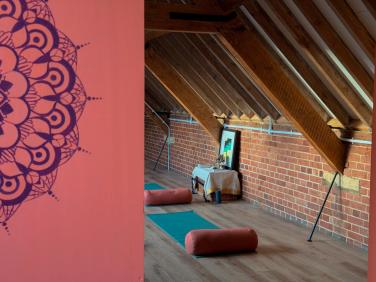 The light-filled practice room with the mandala wall and mats laid out