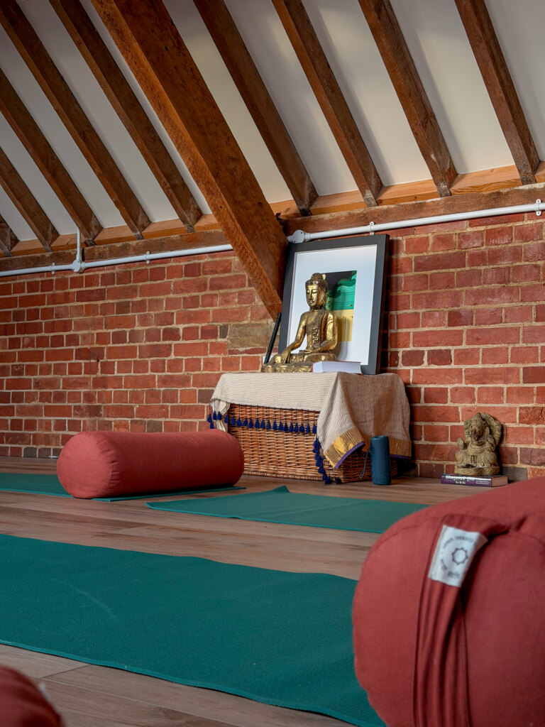 Teal yoga mats and terracotta bolsters ready for practice